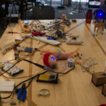 Dolls and electronic parts spread out across a table